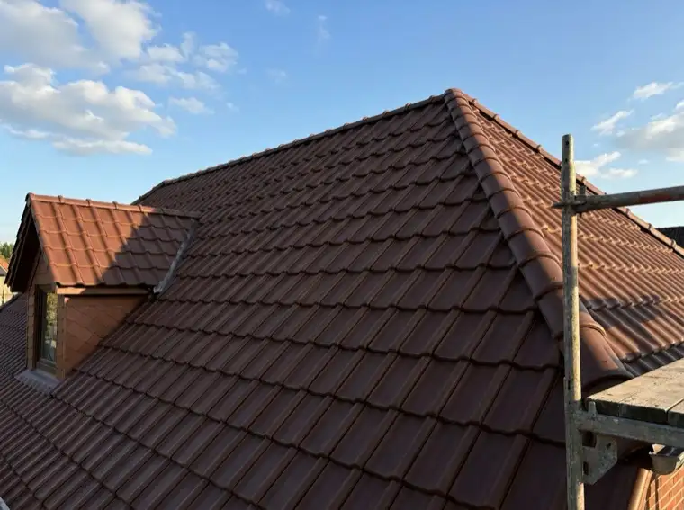 Frisch gedecktes Steildach mit dunkelroten Tonziegeln und kleiner Gaube